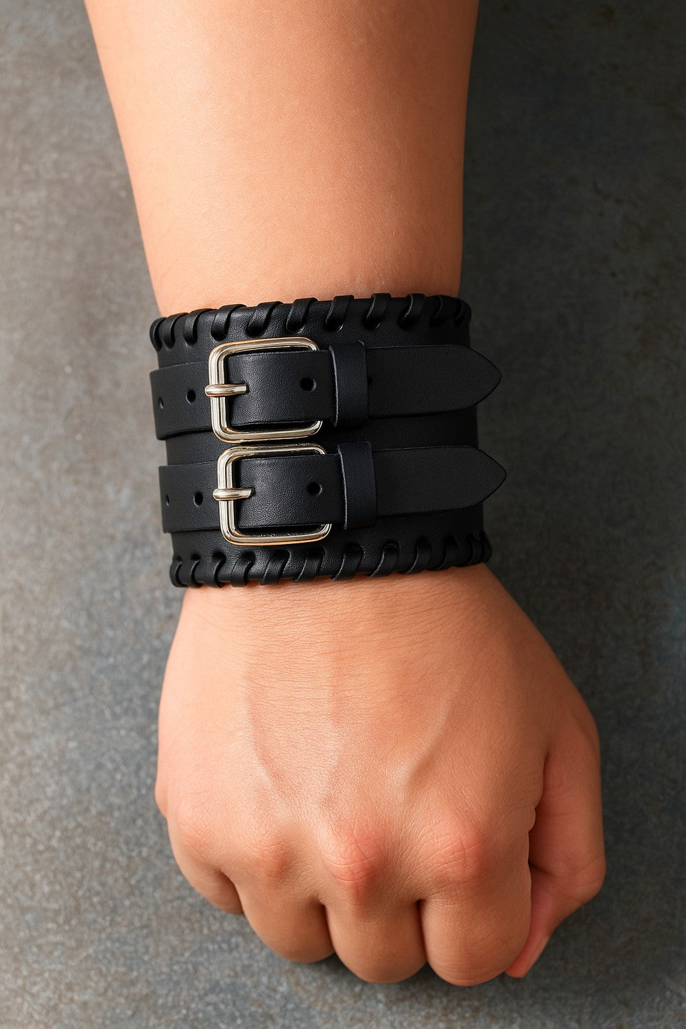 Musta keinonahkainen rannekoru, jossa kaksinkertaiset soljet